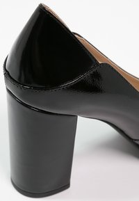 Chaussure pour femme en cuir verni noir avec talon bloc et finition lisse et brillante, vue de côté arrière.