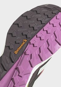 Gummisko sål med sort og lilla mønster, tydelige grebslugger og et synligt Continental-logo i orange på siden.