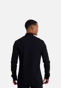 Zwarte long sleeve shirt met een hoge kraag, aansluitend ontwerp en textuurstof. Strakke, minimalistische stijl zonder zichtbare patronen.