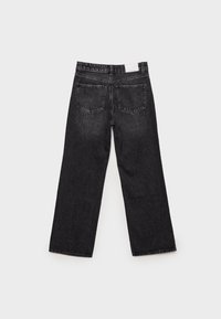 Jean noir à jambes larges vu de dos avec deux poches arrière et une étiquette blanche sur la taille sur un fond uni.
