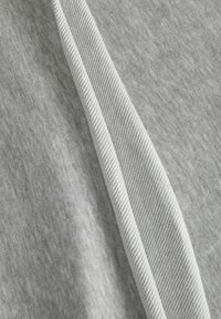 Tela gris con una textura suave, que presenta una costura lisa de un gris más claro a lo largo de uno de los bordes. La composición muestra una vista en primer plano del material.
