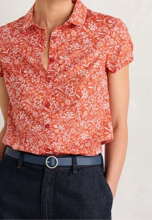 Blusa de manga corta y cuello en un patrón floral naranja. Presenta un cierre de botones en la parte delantera, tejido ligero y un cinturón de cuero azul con hebilla circular.