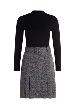 Haut noir à manches longues associé à une jupe grise à motifs avec une ceinture, des plis et un design texturé.