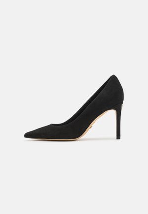 Décolleté nera in suede con punta affusolata e tacco sottile, caratterizzata da una superficie liscia e un design minimalista.