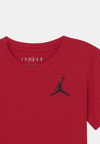 Czerwona bawełniana koszulka T-shirt z czarnym haftowanym logo Jordana po lewej stronie klatki piersiowej, z okrągłym dekoltem i krótkimi rękawami.