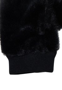 Svart faux fur-hanske med teksturert overdel og ribbestrikket mansjett. Mansjetten har en tettsittende passform med en glatt finish.