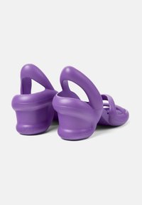 Violet muovatut sandaalit avoimella takana, kaarevalla korolla ja useilla leikatuilla osilla. Valmistettu kevyestä materiaalista, jossa on sileä pinta.