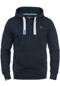 Marineblaues Kapuzenshirt mit einer vorderen Tasche, weißen Kordeln und einem kleinen blauen Logo auf der Brust. Mit gerippten Bündchen und Saum.