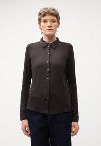 Sort langærmet skjorte med knapper og krave, lavet af glat stof. Har en lige pasform og syv knapper foran til lukning.