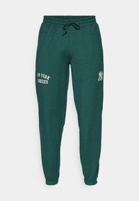 Zaļie sporta bikses ar elastīgu jostu, auklu, sānu kabatām un baltu tekstu "NEW YORK YANKEES". Mīksta auduma tekstūra.