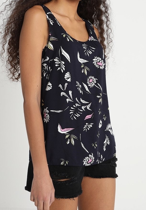 Granatowy top na ramiączkach z kwiatowym wzorem w bieli, różu i zieleni. Lekki materiał, okrągły dekolt, w połączeniu z czarnymi szortami z przetarciami.