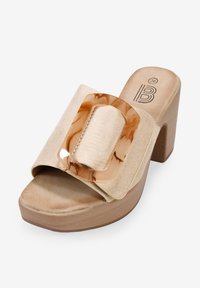 Sandalía de plataforma beige con acabado de ante, que presenta una gran hebilla mate marmoleada. Diseño de tacón cuadrado y punta abierta. Apariencia elegante y moderna.