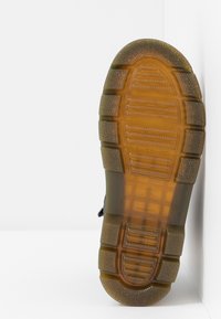 Brown rubber sole with textured grip pattern, featuring horizontal and vertical ridges. Smooth edges with a slight heel elevation.