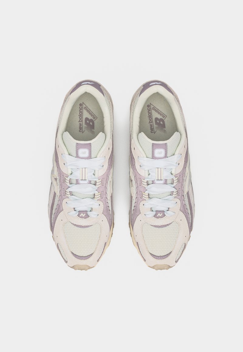 Par de zapatillas para correr New Balance en rosa claro y beige con cordones blancos, vista desde arriba sobre un fondo blanco.
