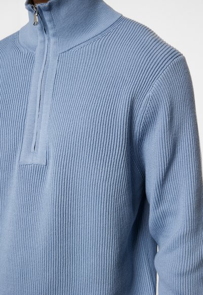 Hellblaues Zip-Up Sweatshirt mit geripptem Textur, mit hohem Kragen und einem Viertelreißverschluss auf der Vorderseite. Weicher Stoff mit eng anliegenden Ärmeln.