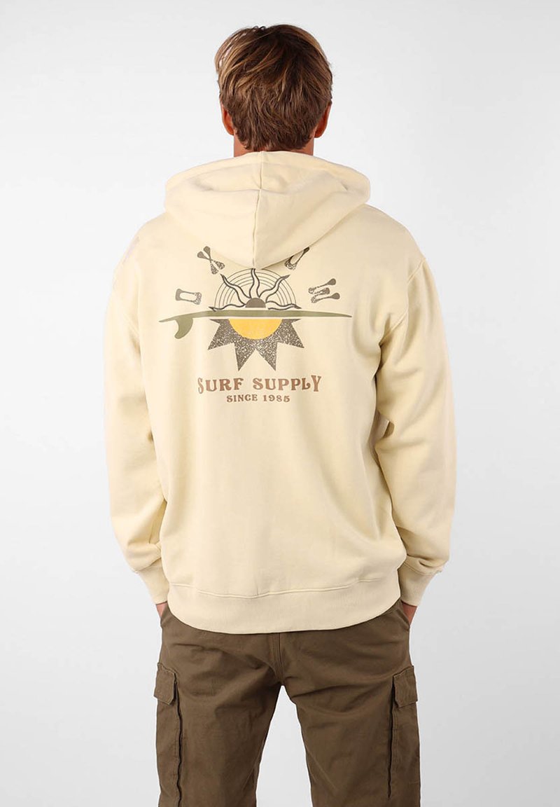Haut à capuche beige clair avec un imprimé graphique présentant des éléments liés au soleil et au surf au dos. Coupe classique, texture douce et capuche avec cordon de serrage.