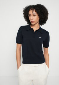 Tengerészkék kötött galléros póló rövid ujjakkal és bordázott szegéllyel, kétgombos sliccel és hímzett "2ND" logóval a mellkason.