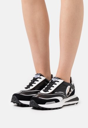 Baskets de sport en noir et blanc avec un mélange de cuir lisse et de daim. Dotées d'une semelle épaisse, d'un bout rond et d'un laçage à l'avant.