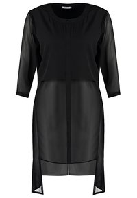 Blouse longue noire transparente avec manches trois-quarts et encolure ronde boutonnée, avec des fentes latérales asymétriques.