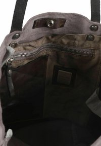 Grijze canvas draagtas interieur met een bruine leren label. Voorzien van een ritsvak en drukknoopsluiting. Zachte textuur met een licht versleten uitstraling.