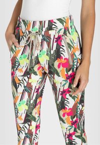 Blomsterprintede bukser med snor i taljen, med sidelommer med lynlås. Farverne inkluderer grøn, pink, orange og beige med en glat tekstur.
