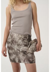 Top a fascia grigio a coste abbinato a una mini gonna brown tie-dye e una borsa a tracolla coordinata. Caratteristiche includono uno scollo a cappuccio e un design aderente.
