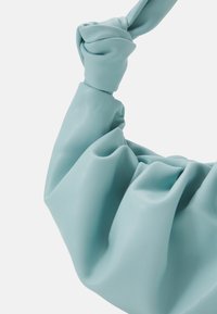 Jasnoniebieska skórzana torba z wiązanym uchwytem, o miękkiej, pomarszczonej fakturze i plisowanym wzorze, podkreślająca gładki, elastyczny materiał.