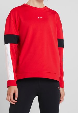 Person iført en rød Nike sweatshirt med sorte og hvide striber på ærmerne og sorte Puma leggings.