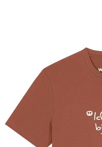 T-shirt à manches courtes de couleur rouille avec un texte partiel imprimé en blanc sur le devant, montré découpé depuis le coin supérieur droit.