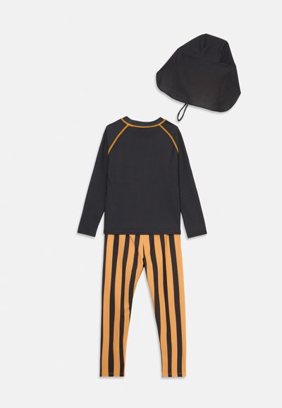 Μαύρο τοπ με μακριά μανίκια και πορτοκαλί ραφές, συνδυασμένο με κίτρινο-πορτοκαλί ριγωτό κολάν και αντίστοιχο καπέλο. Μαλακό ύφασμα, αθλητικός σχεδιασμός.