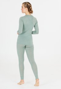 Lichtgroene langemouwen top en bijpassende leggings gemaakt van zachte, gladde stof. Strakke pasvorm met manchetten aan de mouwen en enkels.
