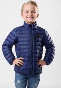 Giacca imbottita blu navy con colletto alto, chiusura con cerniera frontale e tasca sul petto sinistro; presenta una texture trapuntata e polsi elastici.