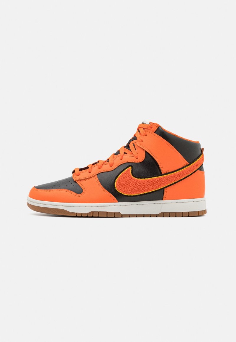 Středně vysoké tenisky s oranžovým a černým koženým svrškem, texturovaným žlutým prošíváním a černým logem swoosh, zakončené gumovou podrážkou.