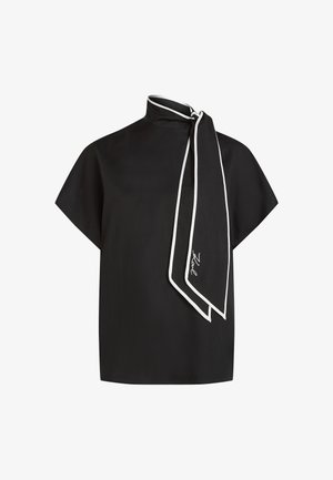 Μαύρο μπλουζάκι με κοντά μανίκια, υψηλό γιακά και μια μακριά προσαρτημένη φουλάρι με λευκό τελείωμα, που διαθέτει χαρακτηριστική λεπτομέρεια κοντά στο τέλος του φουλαριού.