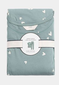 Pijamas de manga corta y pierna larga en algodón azul claro con estampado de corazones blancos. Empaquetados con una banda en blanco y negro alrededor.