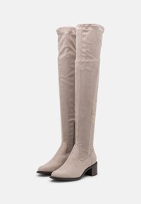 Botas de ante sintético de color beige claro, hasta la rodilla, con tacón cuadrado y cremallera lateral. Textura suave y diseño simple y aerodinámico.