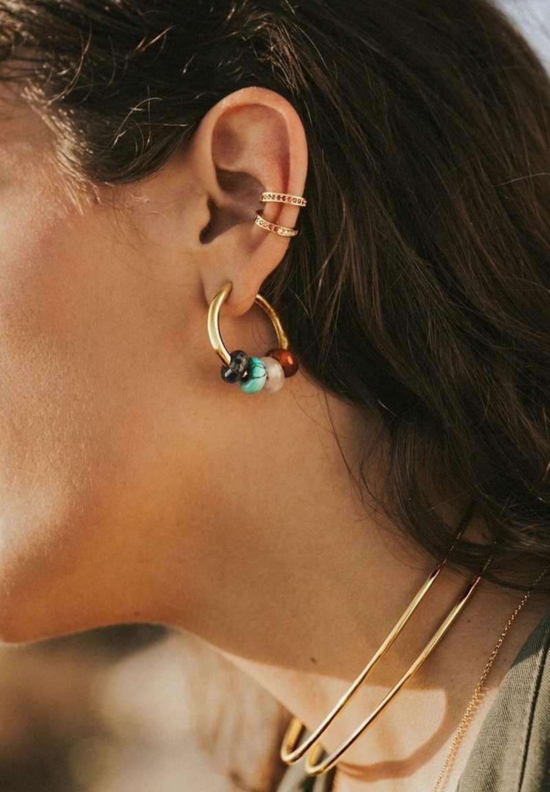 Boucle d'oreille en or avec des perles colorées (turquoise, rouge, noir et orange) et deux manchons d'oreille en or. Texture lisse, design circulaire.