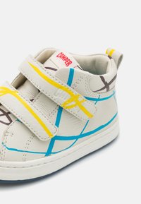 Baskets en cuir blanc avec des lignes graphiques bleues, jaunes et marron. Dotées de bandes Velcro et d'une cheville rembourrée. Logo Camper sur la languette.
