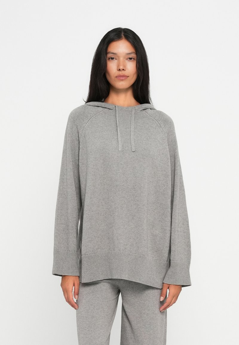 Hoodie cinza de malha com textura canelada, de corte largo, mangas raglan e cordão ajustável. Combinado com calças cinzas a condizer.