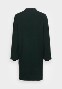 Pull en maille oversize vert foncé avec un col montant, des épaules tombantes et des manches longues, doté de poignets côtelés et d'un design simple.
