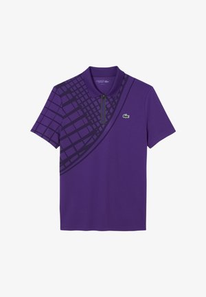 Polo shirt viola con colletto con zip, maniche corte e un motivo geometrico di un viola più scuro su un lato. Logo Lacoste visibile.