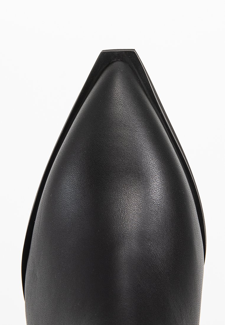 Scarpa nera in pelle con punta affusolata, caratterizzata da un design elegante, una superficie liscia e una silhouette strutturata con un sottile dettaglio a taglio.