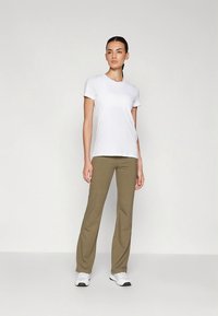 Fehér rövid ujjú póló olívazöld nadrággal párosítva, laza szabással, sima textúrával és finom dizájnelemekkel.