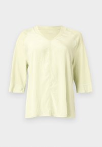 Ανοιχτό κίτρινο T-shirt με V-λαιμόκοψη, μανίκια τριών τετάρτων και ορατές ραφές μπροστά και στα μανίκια.