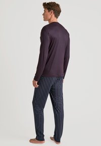 Haut à manches longues de couleur violet foncé associé à un pantalon de pyjama rayé bleu marine et blanc. Le tissu semble doux, avec une coupe décontractée et un design léger.
