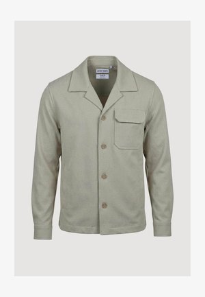 Lysebeige jakke med lange ærmer, krave, knaplukning foran og en enkelt klaplomme på venstre bryst.