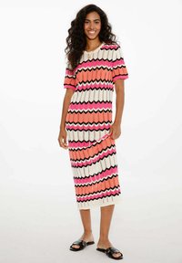 Pletené šaty s cik-cak vzorem v růžové, oranžové, černé a krémové barvě. Krátké rukávy a délka po polovinu lýtek. Snadno se oblékají.