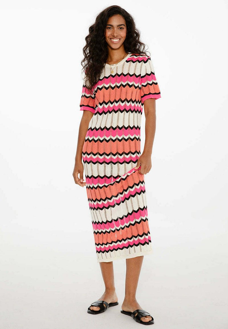 Pletené šaty s cik-cak vzorem v růžové, oranžové, černé a krémové barvě. Krátké rukávy a délka po polovinu lýtek. Snadno se oblékají.
