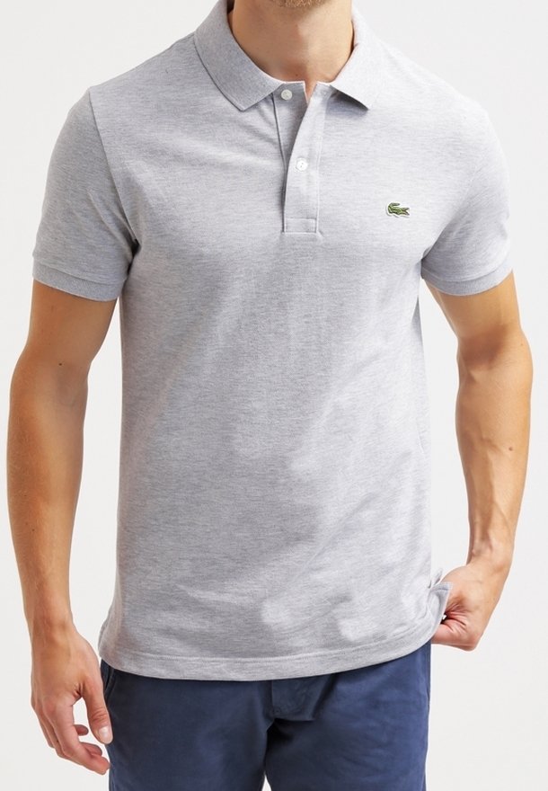 Polo shirt en coton gris avec un col, patte de boutonnage à trois boutons, manches courtes et un logo vert sur la poitrine gauche. Texture lisse.