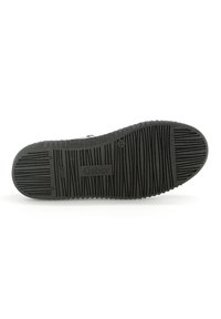 Semelle de chaussure en caoutchouc noir avec un motif de grip texturé et du branding. Présente des lignes et des crêtes surélevées pour l'adhérence et la durabilité.